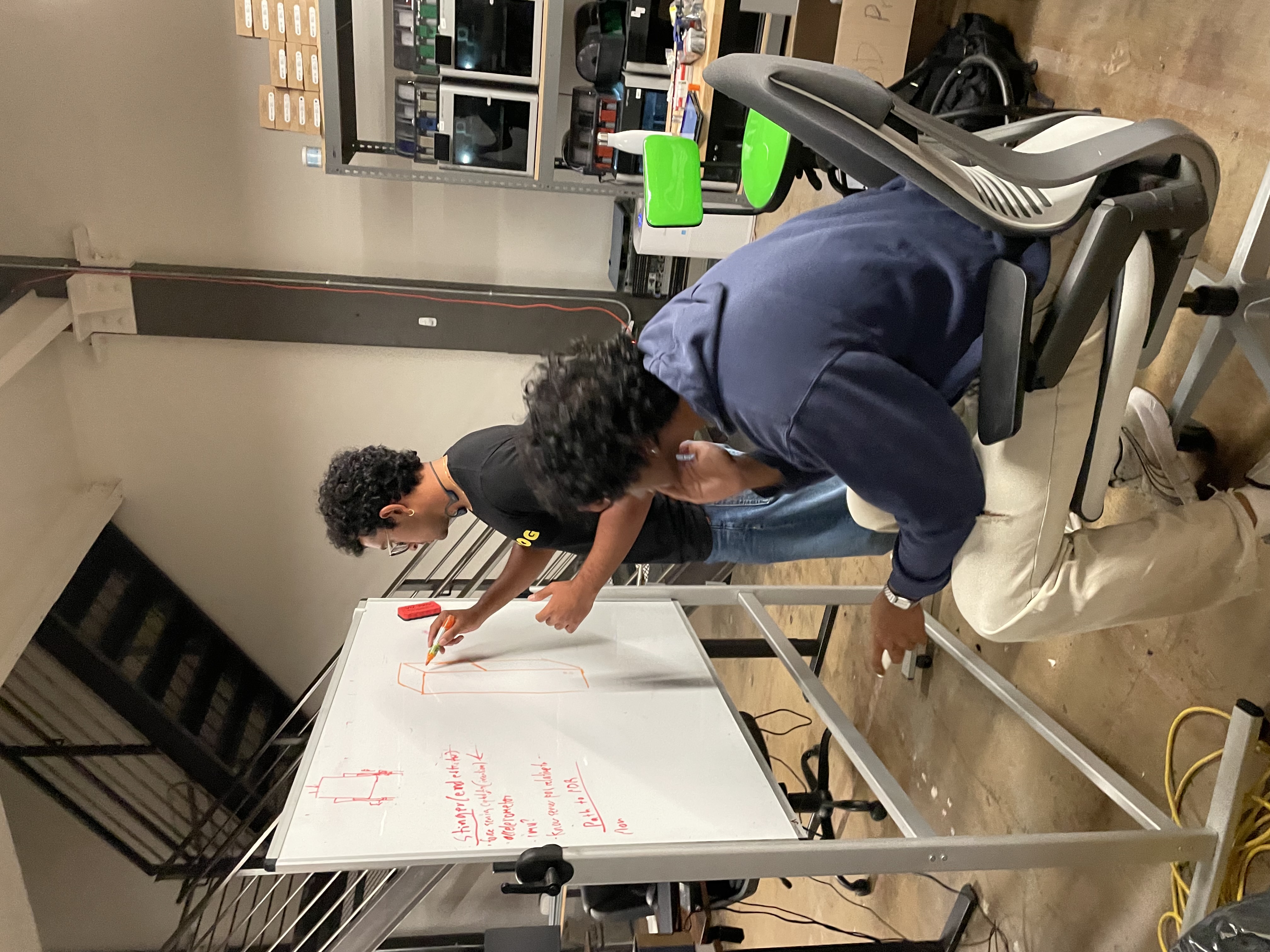 Team brainstorming robot design at whiteboard